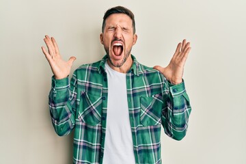 Fototapeta premium Handsome man with beard wearing casual clothes celebrating mad and crazy for success with arms raised and closed eyes screaming excited. winner concept