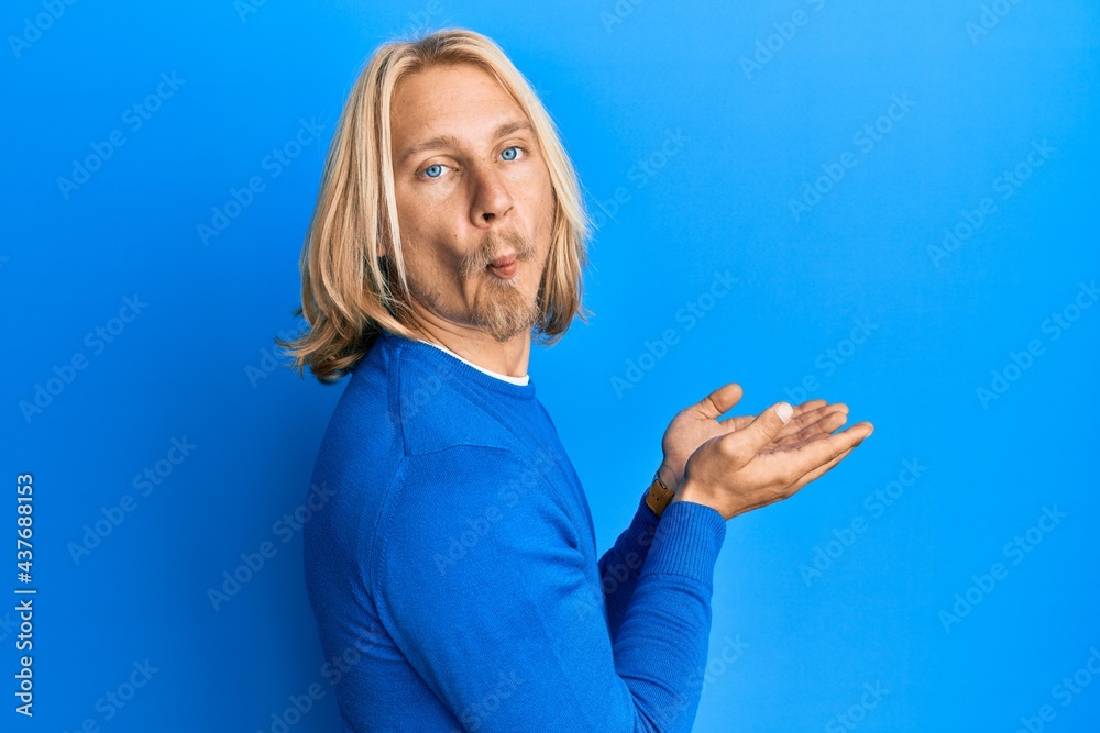 Sticker Caucasian young man with long hair presenting with open palms, holding something making fish face with mouth and squinting eyes, crazy and comical.