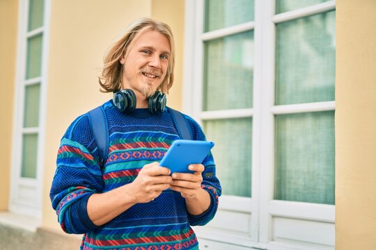 Young scandinavian student man using headphones and touchpad at the city.