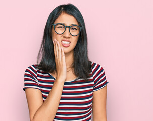 Beautiful asian young woman wearing casual clothes and glasses touching mouth with hand with painful expression because of toothache or dental illness on teeth. dentist