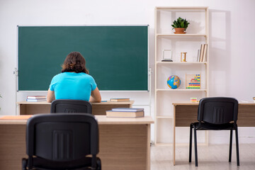 Young male student in front of green board