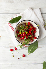 Fresh sour cherry in enamel bowl on white wooden table