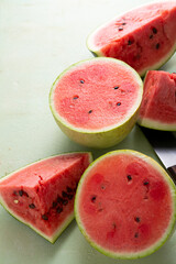 Sliced ripe red watermelon on light green surface