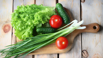 Lettuce, green onions, tomatoes, cucumbers. Set of fresh vegetables on a wooden board. Healthy diet concept.