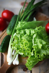 Lettuce, green onions, tomatoes, cucumbers. Set of fresh vegetables on a wooden board. Healthy diet concept.