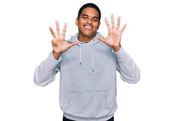 Young handsome hispanic man wearing casual sweatshirt showing and pointing up with fingers number...