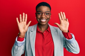 Naklejka premium Young african american woman wearing business jacket and glasses showing and pointing up with fingers number nine while smiling confident and happy.