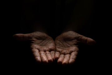 Begging, empty palms, outstretched hands. Concept of social disadvantage, black background.