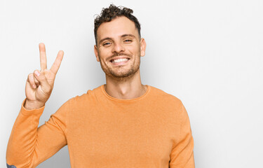 Young hispanic man wearing casual clothes showing and pointing up with fingers number two while smiling confident and happy.