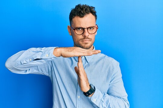 Young hispanic man wearing casual clothes and glasses doing time out gesture with hands, frustrated and serious face