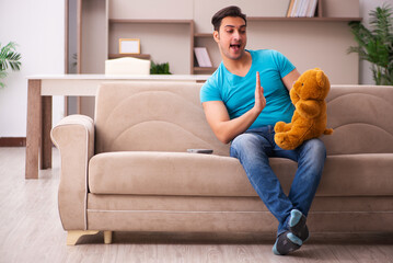 Young man sitting with bear toy at home