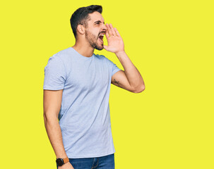 Young hispanic man wearing casual clothes shouting and screaming loud to side with hand on mouth. communication concept.