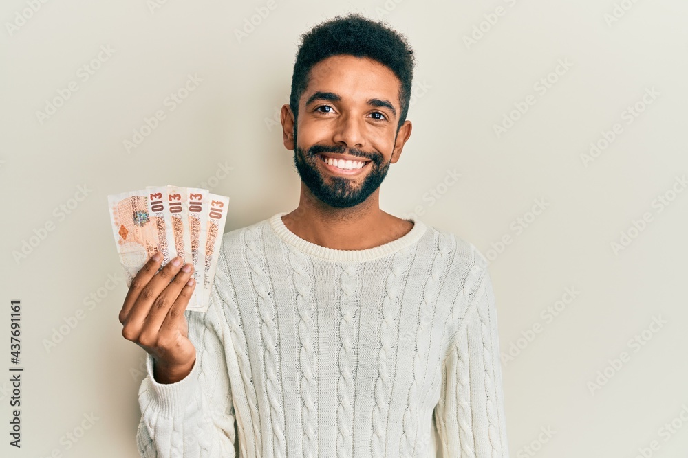 Canvas Prints Handsome hispanic man with beard holding 10 united kingdom pounds banknotes looking positive and happy standing and smiling with a confident smile showing teeth