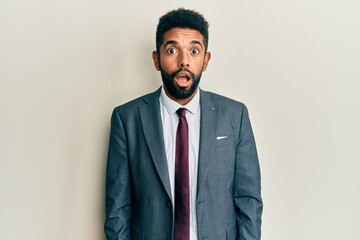 Handsome hispanic man with beard wearing business suit and tie afraid and shocked with surprise and amazed expression, fear and excited face.