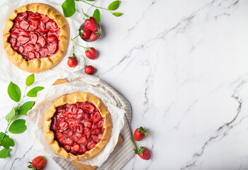 Homemade galettes with strawberries on white marble background