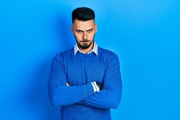 Young hispanic man with beard wearing casual blue sweater skeptic and nervous, disapproving expression on face with crossed arms. negative person.