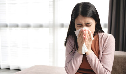 Young Asian women cover their mouth and nose with tissues during the flu, coughing and sneezing to prevent spreading the virus. Concept of health care and medicine - obrazy, fototapety, plakaty