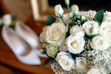 wedding bridal bouquet of white roses on the background of the bride's beige shoes in blur