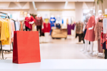 Red paper shopping bags with abstract blurred background of interior clothing store at Shopping Mall