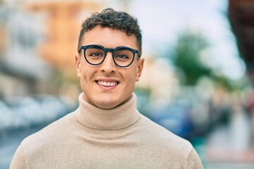 Young hispanic man smiling happy wearing glasses at the city.