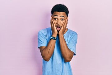 Young african american man wearing casual blue t shirt afraid and shocked, surprise and amazed expression with hands on face