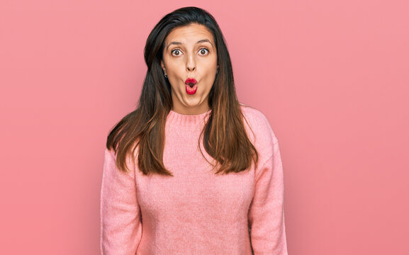 Beautiful hispanic woman wearing casual winter sweater scared and amazed with open mouth for surprise, disbelief face