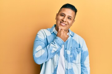 Young latin man wearing casual clothes smiling looking confident at the camera with crossed arms and hand on chin. thinking positive.