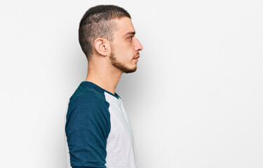 Hispanic young man wearing casual clothes looking to side, relax profile pose with natural face with confident smile.