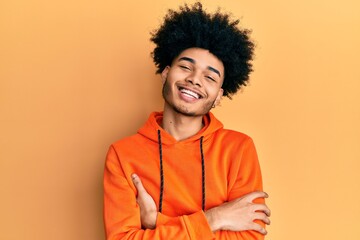 Fototapeta na wymiar Young african american man with afro hair wearing casual sweatshirt happy face smiling with crossed arms looking at the camera. positive person.