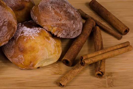 freshly baked cinnamon rolls on a wooden background with cinnamon sticks