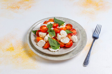 Delicious Italian caprese salad with sliced red and orange cherry tomatoes and mozzarela balls.