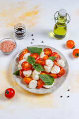 Delicious Italian caprese salad with sliced red and orange cherry tomatoes and mozzarela balls.