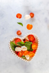 Delicious Italian caprese salad with sliced red and orange cherry tomatoes and mozzarela balls.