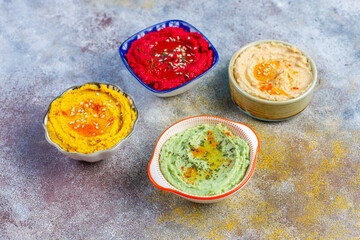 Traditional Middle eastern food various hummus. Green,yellow,beet and traditional hummus in small bowls.