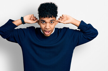 Young african american man wearing casual clothes smiling pulling ears with fingers, funny gesture....