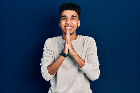 Young african american man wearing casual clothes praying with hands together asking for forgiveness smiling confident.