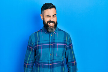 Young hispanic man wearing casual clothes winking looking at the camera with sexy expression, cheerful and happy face.