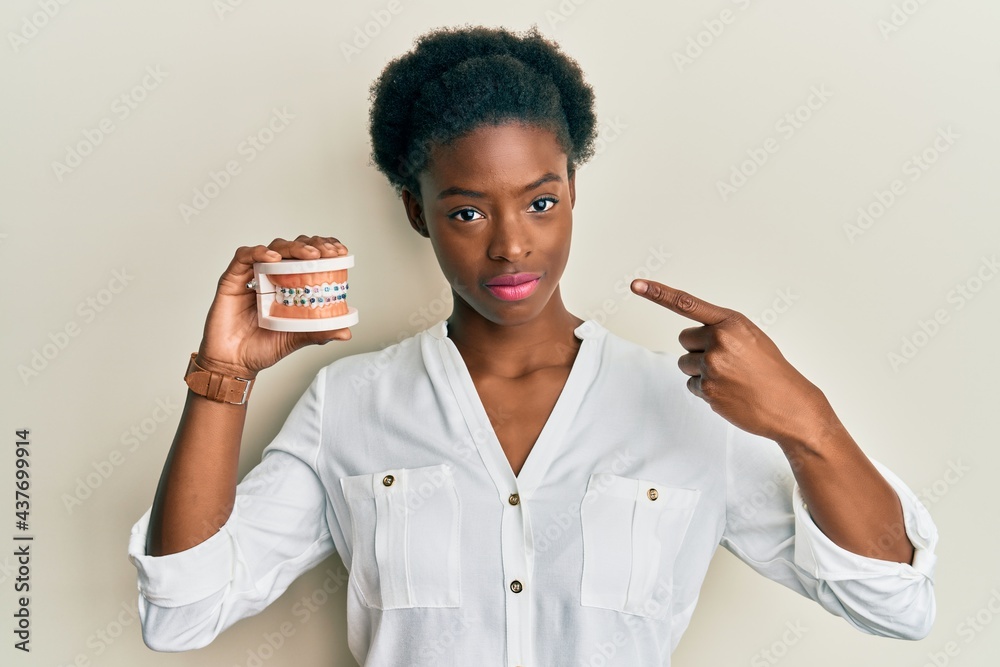 Canvas Prints Young african american girl holding orthodontic relaxed with serious expression on face. simple and natural looking at the camera.