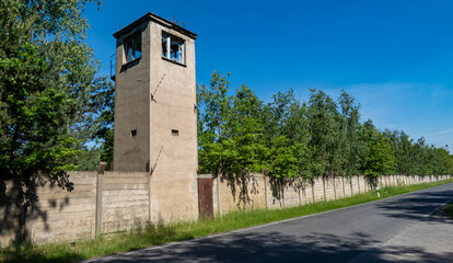 Fototapeta na wymiar verlassener alter Wachturm mit Betonzaun und Bäumen mit einer Straße im Vordergrund