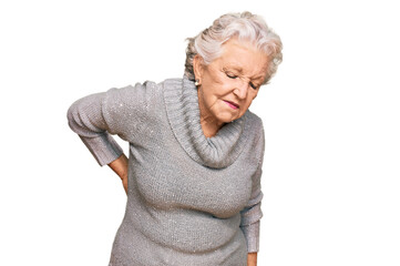 Senior grey-haired woman wearing casual winter sweater suffering of backache, touching back with hand, muscular pain