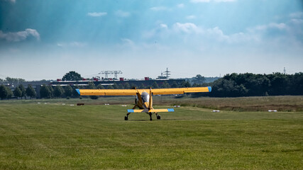 Fototapeta na wymiar Rückansicht eines startenden einmotorigen Flugzeugs bei leicht wolkigem Himmel