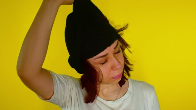 Close up of unrecognizable person in black balaclava on yellow background. Young woman removes mask and reveals identity