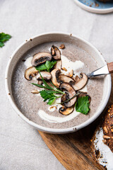 Fototapeta na wymiar Traditional French mushroom cream soup with sour cream and parsley and rye bun on wooden board on natural linen background .