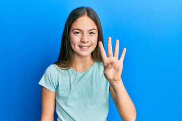 Fototapeta premium Beautiful brunette little girl wearing casual white t shirt showing and pointing up with fingers number four while smiling confident and happy.