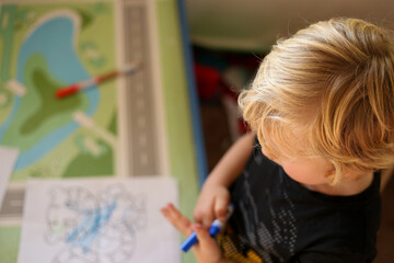Top down view of small  child sitting at kid's table drawing pictures