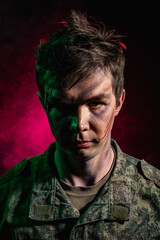 Portrait of a young soldier in uniform and combat coloring with bruises and scars on a black...