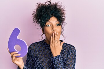 Young hispanic woman holding number six covering mouth with hand, shocked and afraid for mistake....