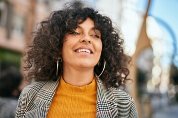 Young hispanic businesswoman smiling happy standing at the city.