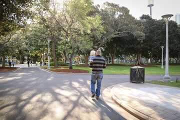 Naklejka premium Father carrying young son while walking through Hyde Park in Sydney, New South Wales Australia
