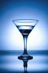 martini glass with olive in blue backlight